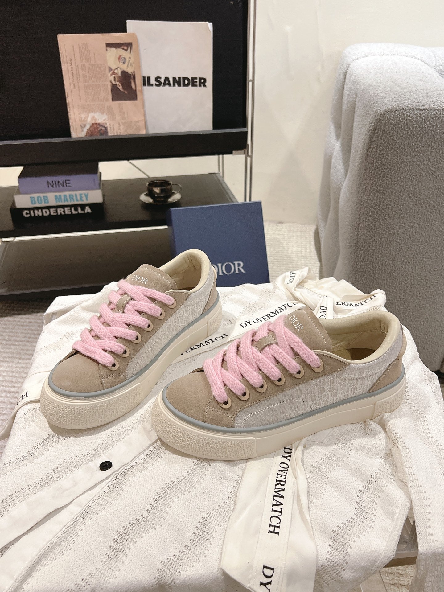 Pair of low-top sneakers in light beige with pink shoelaces and branded side trim