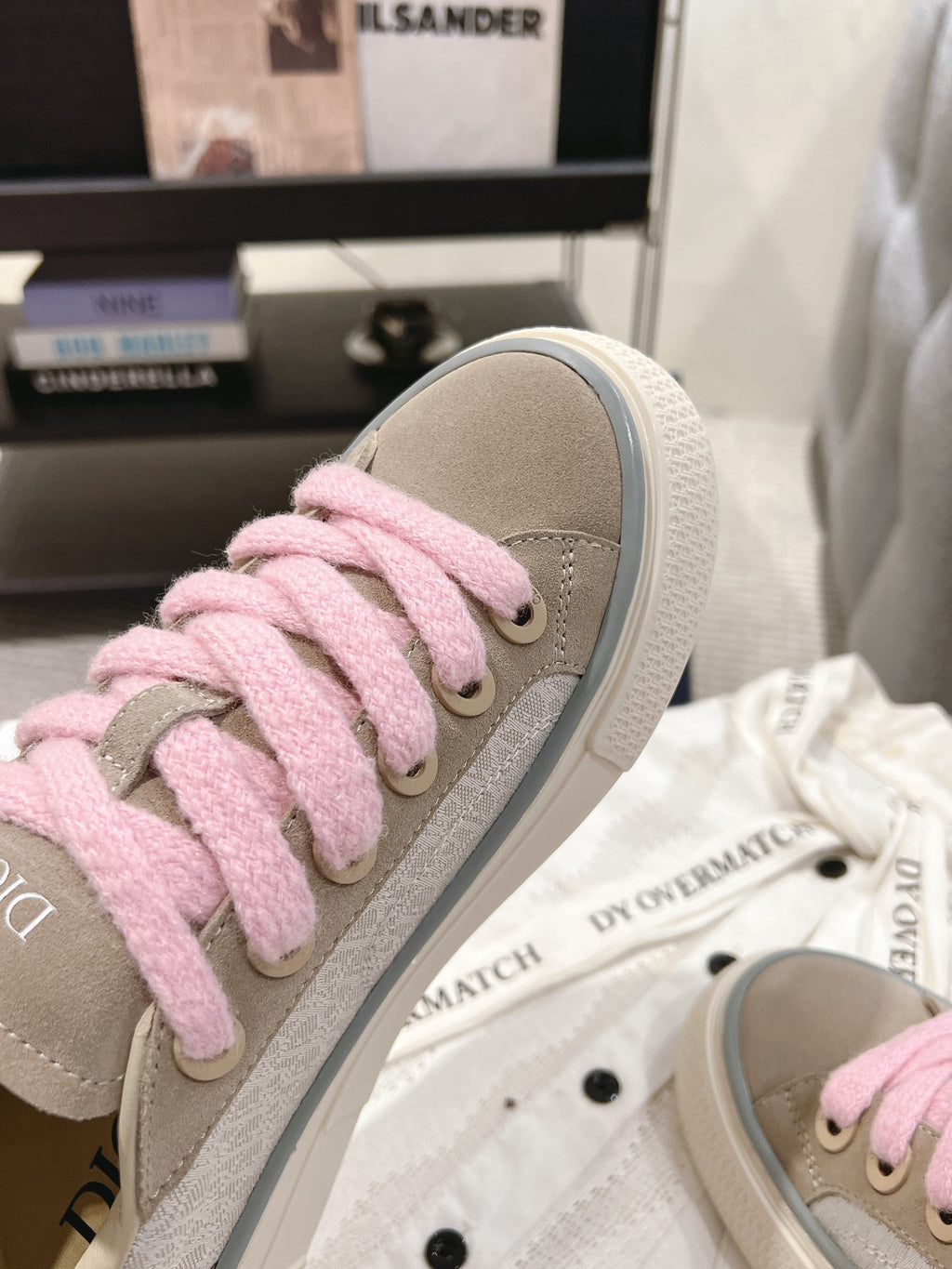 Side view of light beige sneaker with pink lace-up front and textured fabric upper