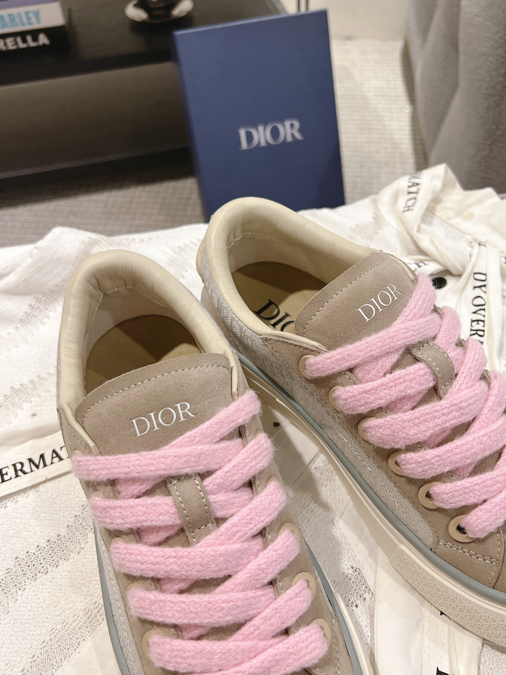 Two low-top sneakers with pink laces, beige uppers, and DIOR logo on side panels