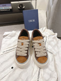 Pair of beige and brown low-top sneakers with white rubber sole and lace-up front
