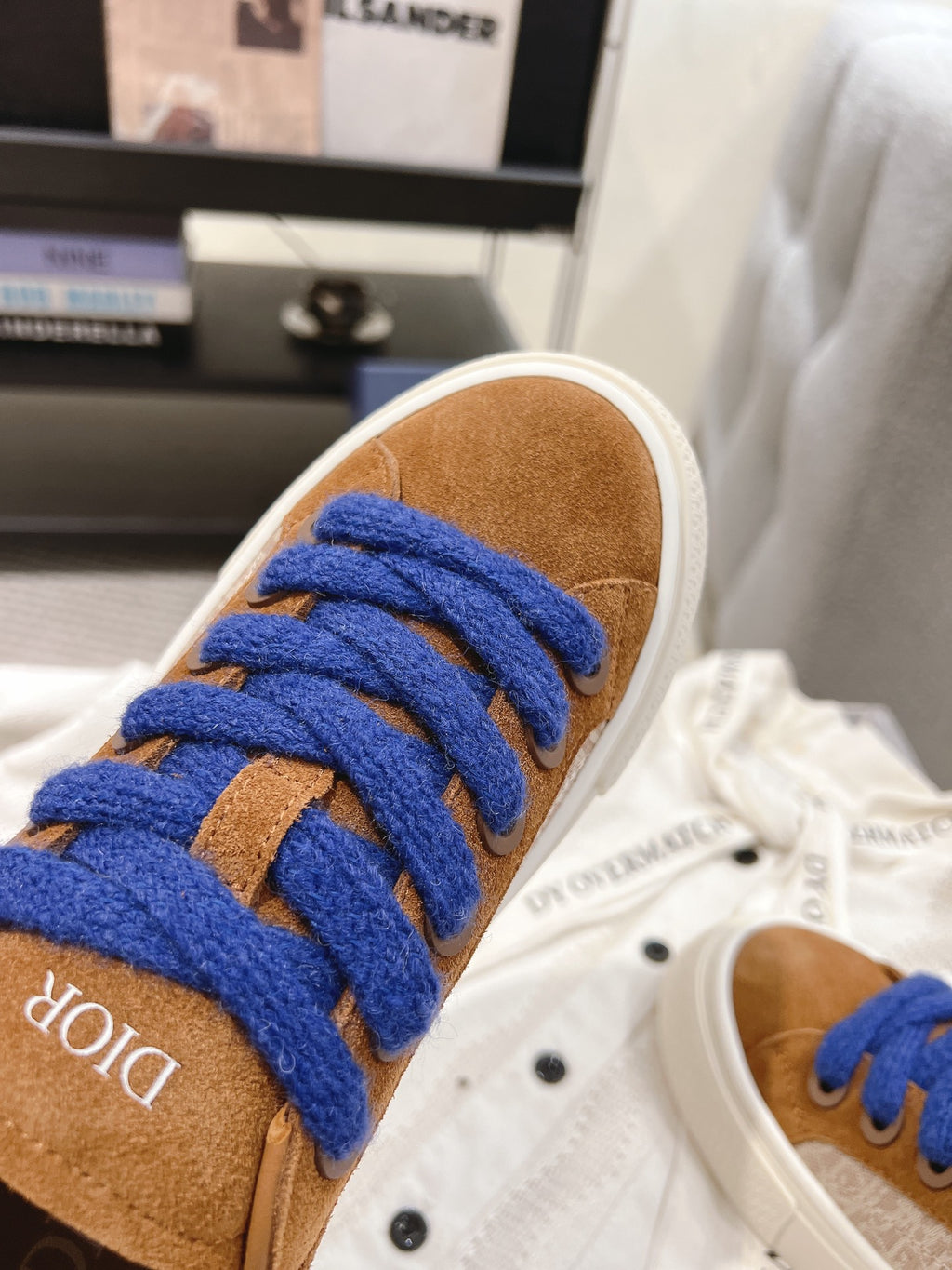 Close-up of tan suede sneaker with bright blue laces and white rubber toe cap