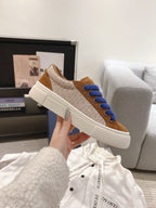 Side view of tan sneaker with blue laces and textured white sole