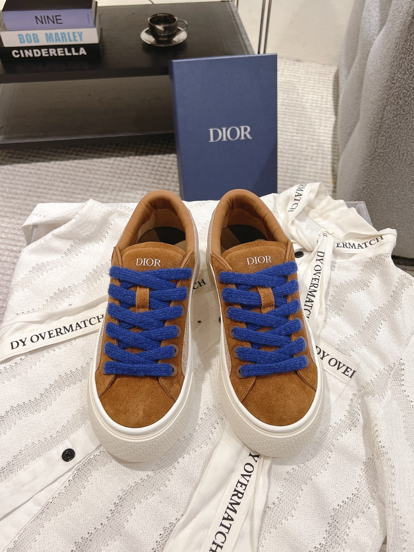 Tan low-top sneaker with bright blue laces and white rubber sole, Dior tongue patch