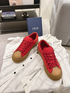 Red lace-up low-top sneakers with tan sole, front angled view of the pair