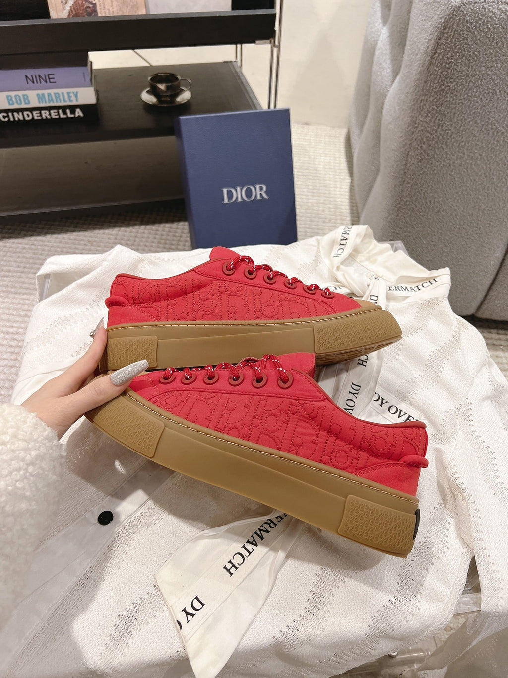 Two red lace-up low-top sneakers stacked, tan soles visible with branding