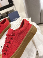 Red lace-up low-top sneaker with tan sole, side view on white dust bag