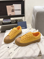 Yellow lace-up low-top unisex sneakers, side view with tan rubber sole