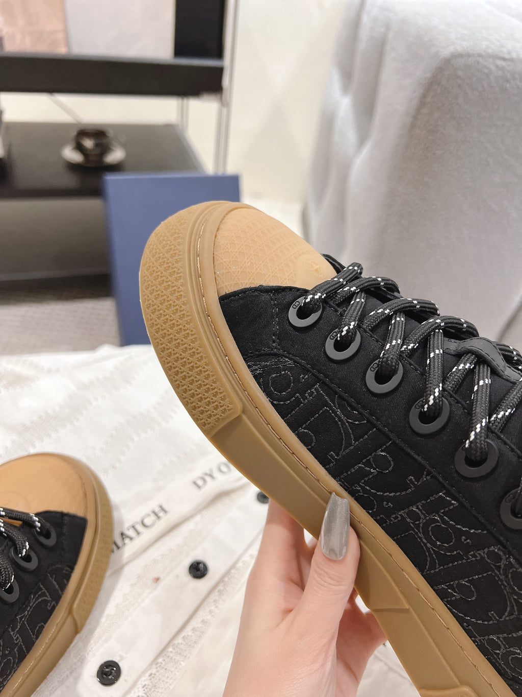 Black Dior sneaker side view with tan sole and black lace-up eyelets