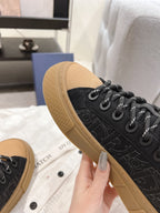 Black Dior sneaker side view with tan sole and black lace-up eyelets