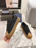 Black Dior lace-up sneakers with tan soles held in hand