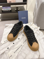 Pair of black Dior lace-up sneakers with tan soles on white cloth