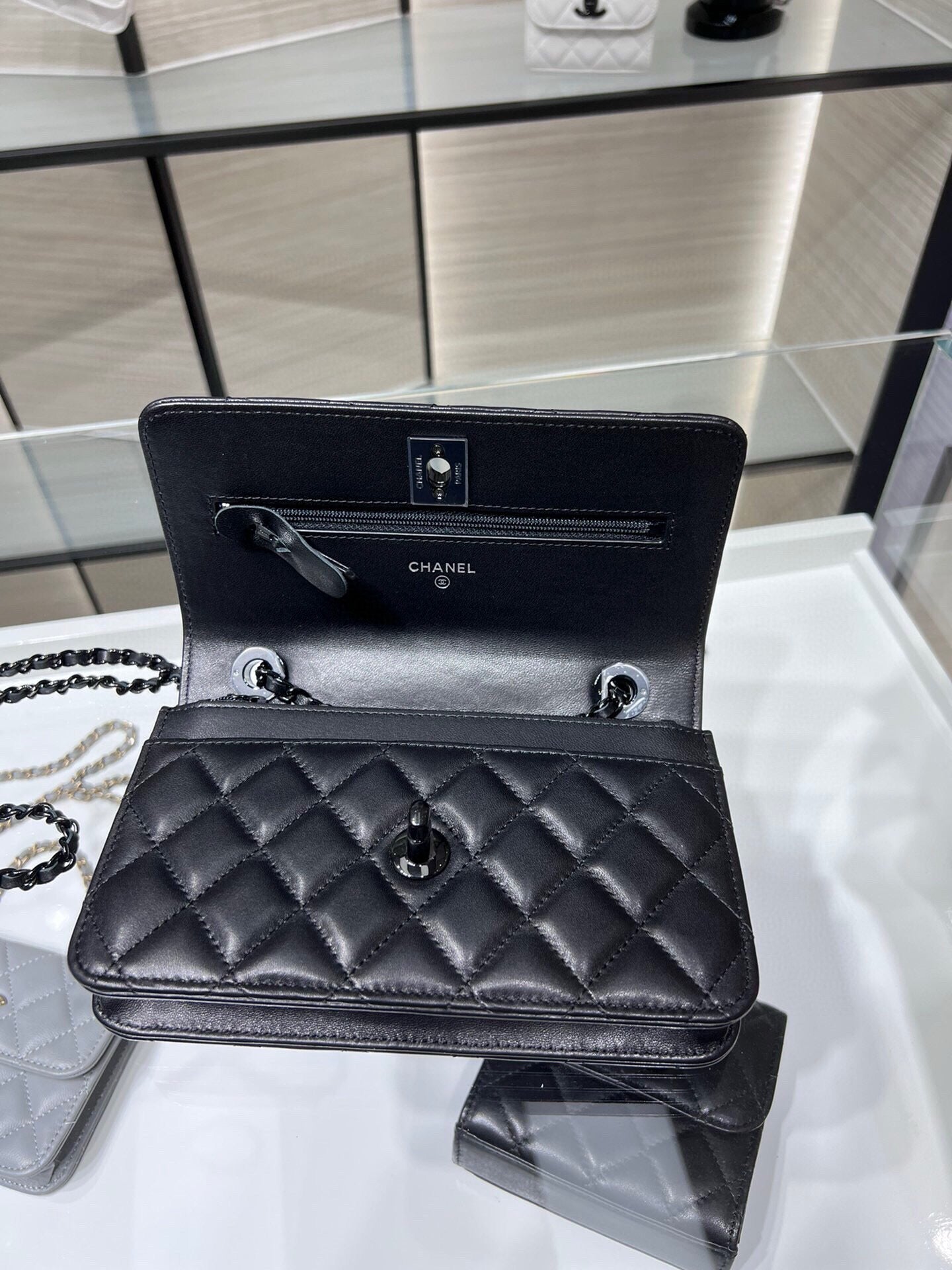 Black quilted leather flap bag open view with interior pocket and chain strap