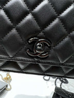 Close-up of black quilted leather flap bag with CC emblem metal clasp