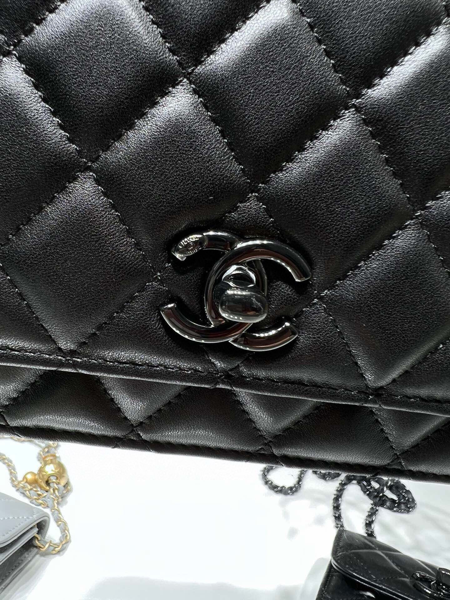 Close-up of black quilted leather flap bag with CC emblem metal clasp