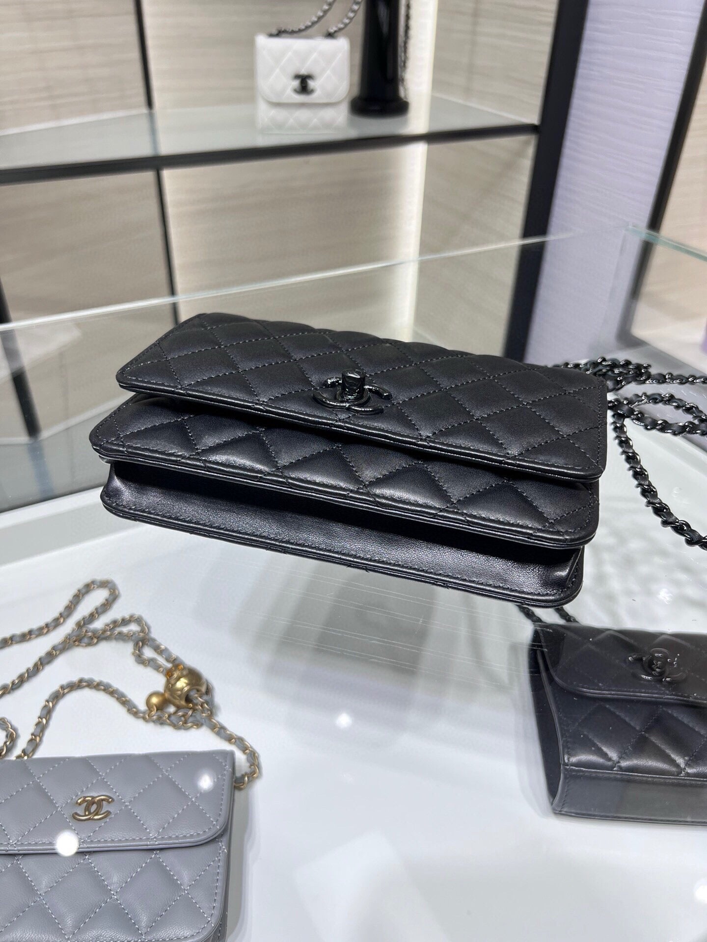 Black quilted leather flap bag with top foldover and chain strap on display