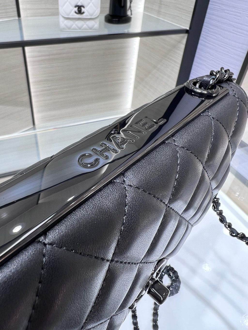Black quilted leather flap bag with chain strap and curved front clasp