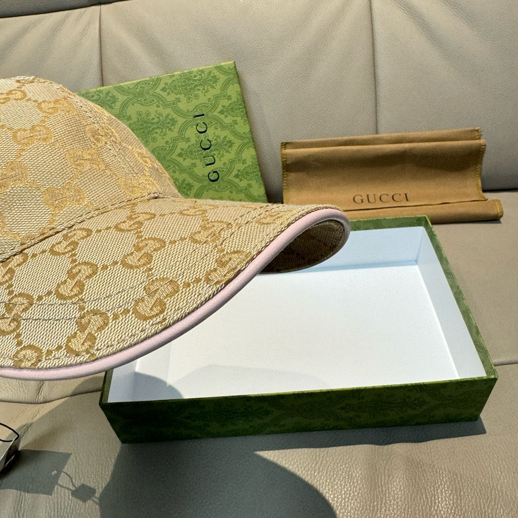 Gucci cap close-up with beige GG monogram fabric and pink underside trim.