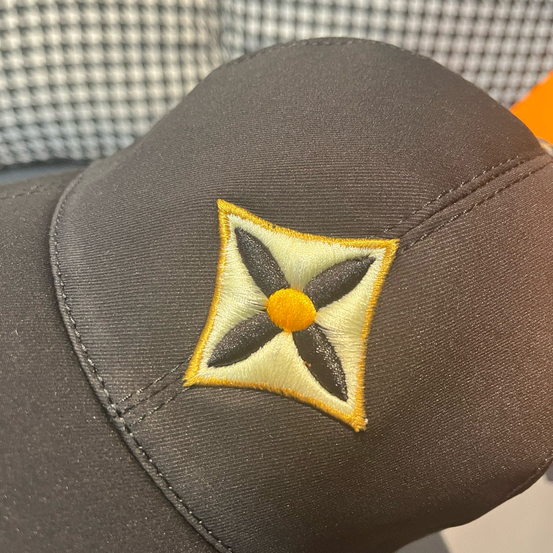 Louis Vuitton cap with close-up of yellow-and-black geometric logo patch on dark crown.
