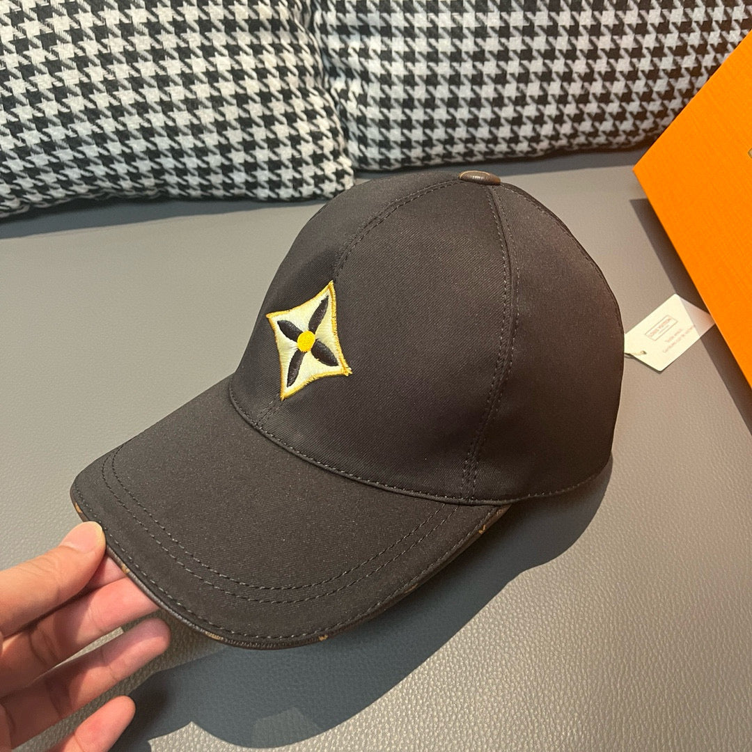 Louis Vuitton cap in dark fabric with yellow-and-black emblem, shown from side angle.