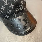 Close-up of Louis Vuitton monogram cap brim with dark leather-like finish and logos