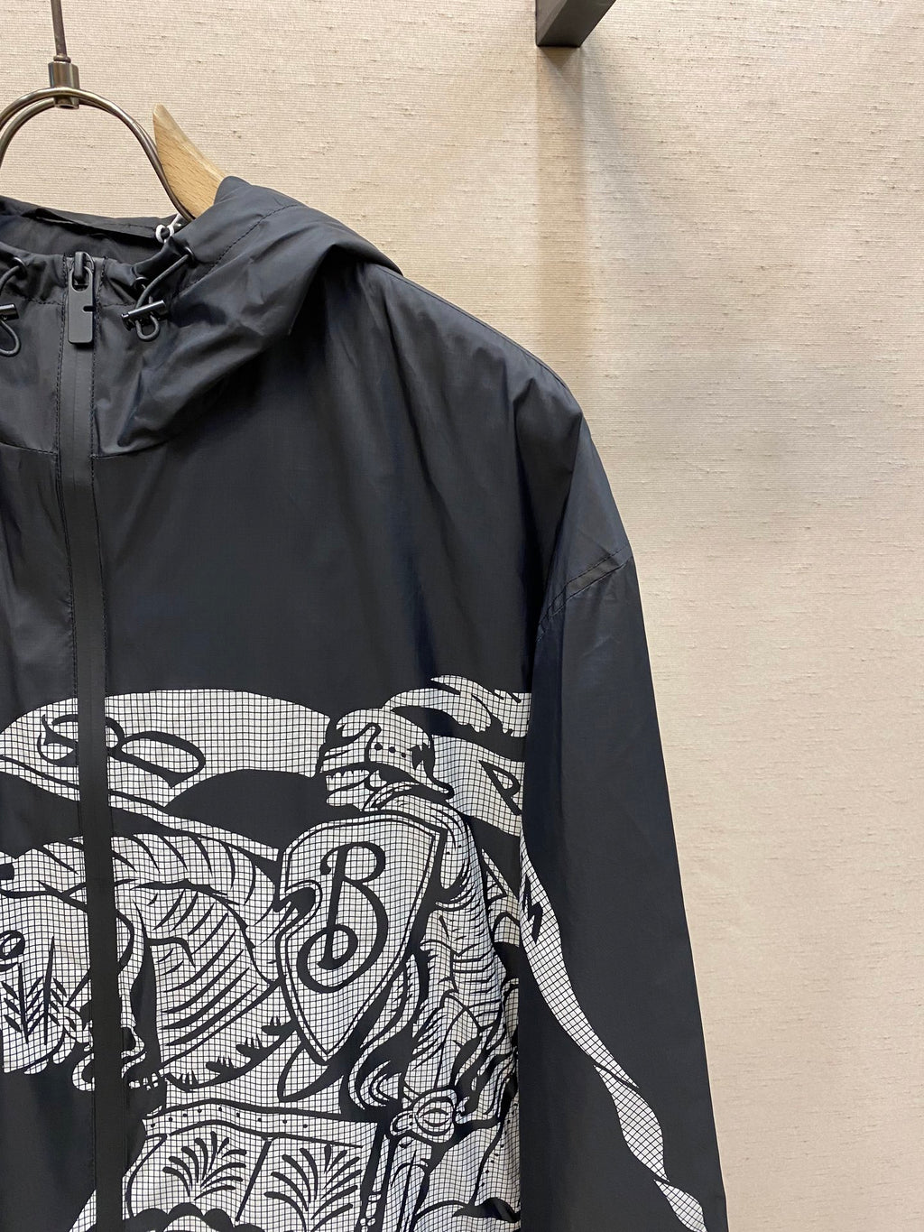 Hooded jacket sleeve close-up with black fabric and white graphic panel