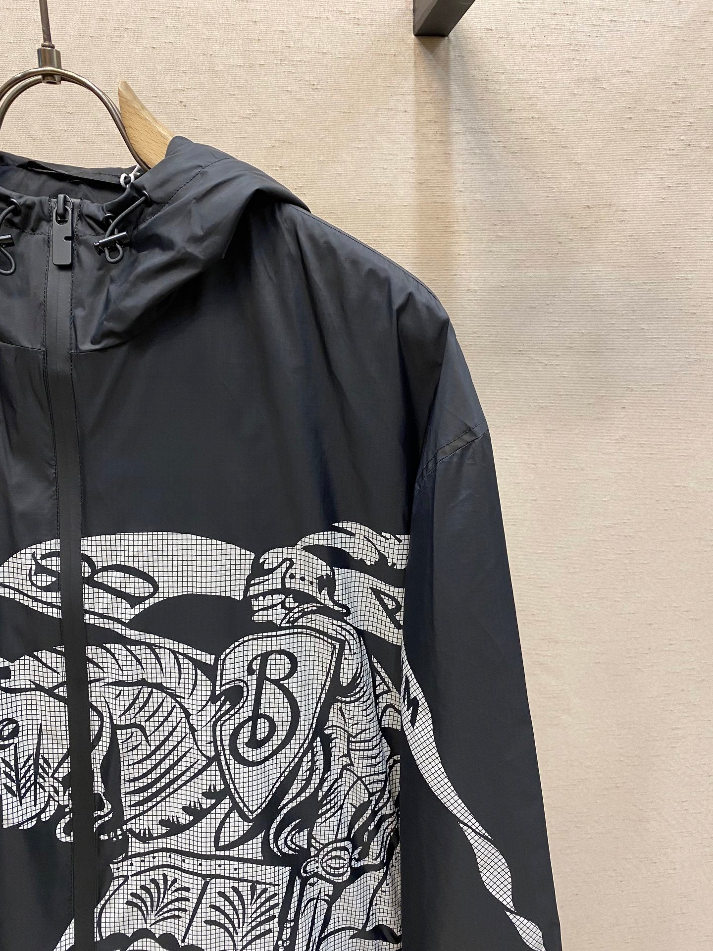 Hooded jacket sleeve close-up with black fabric and white graphic panel