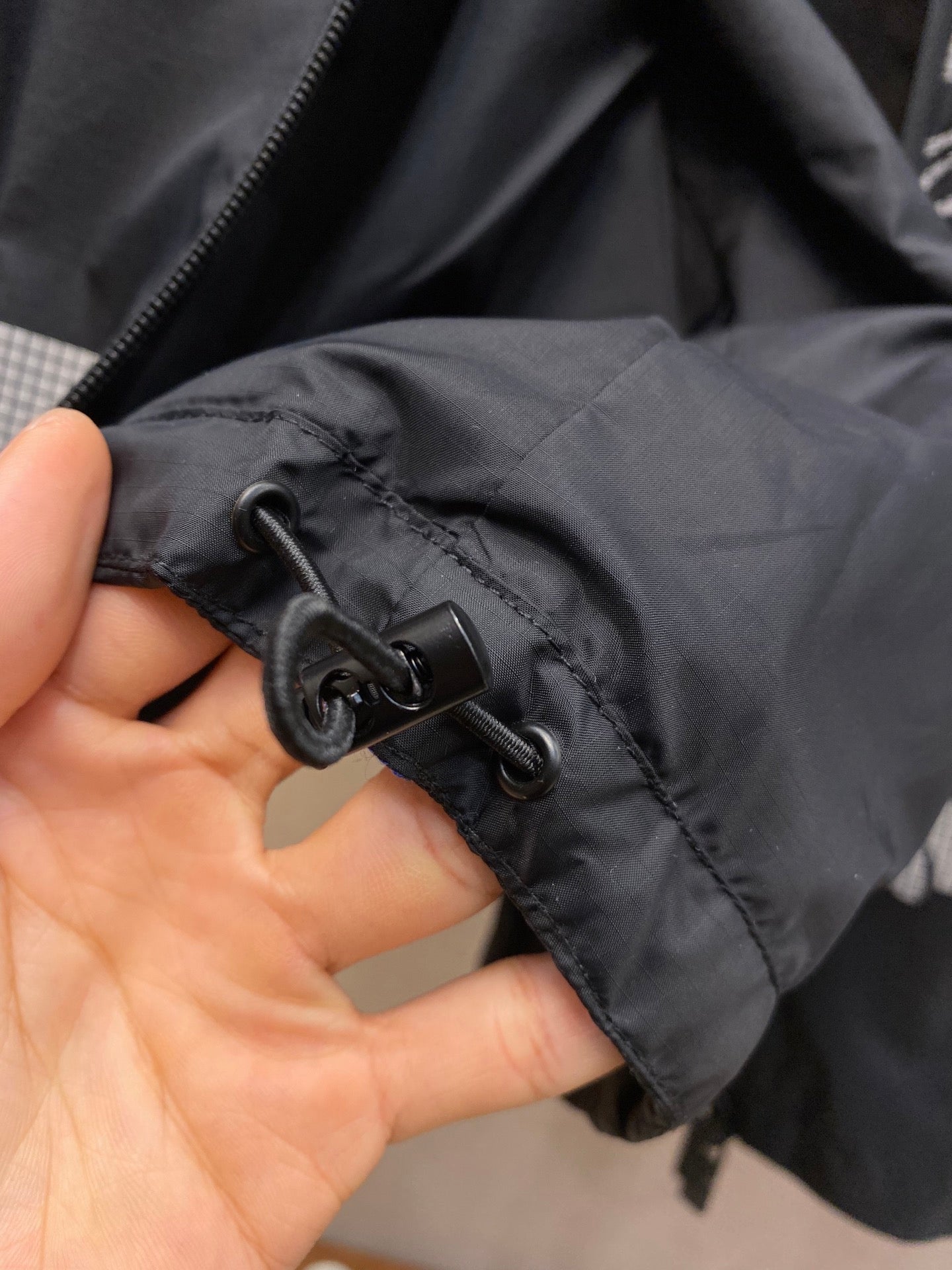 Hooded jacket cuff with drawstring toggle and black zipper tape
