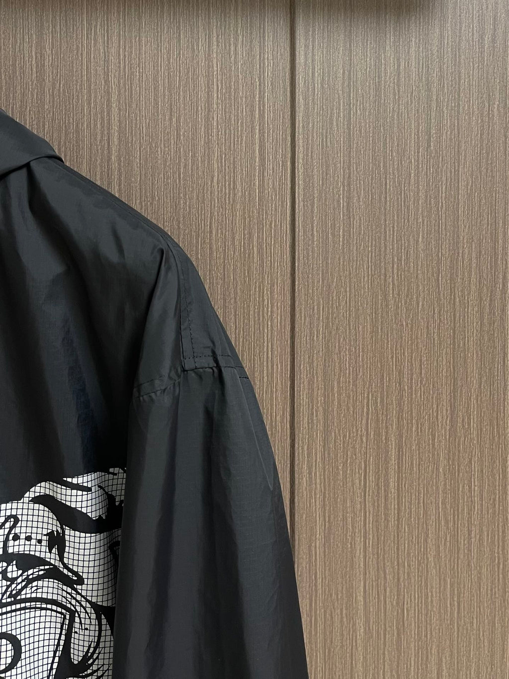 Black jacket sleeve and side panel with white graphic print