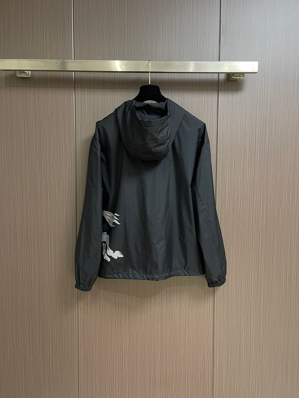 Black zip-up hooded jacket with partial white graphic print, back view