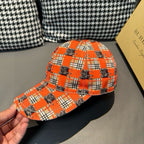 Orange plaid baseball cap held by hand, showing curved brim and horse pattern