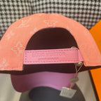 Louis Vuitton monogram cap with adjustable strap, pink label on underside and peach crown.