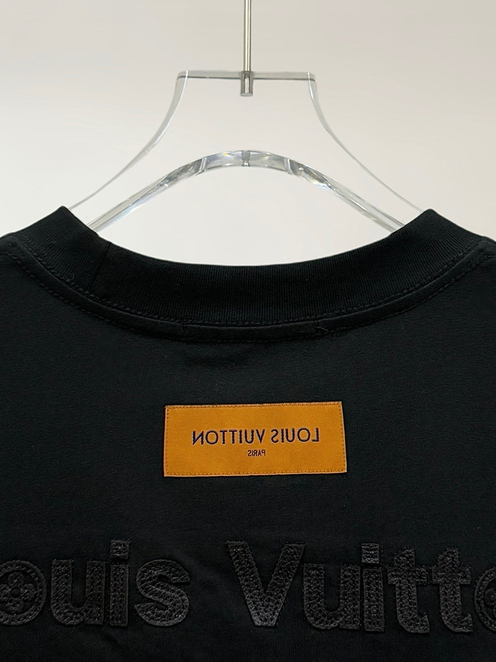 Black T-shirt collar with orange label and embossed Louis Vuitton text