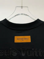 Black T-shirt collar with orange label and embossed Louis Vuitton text