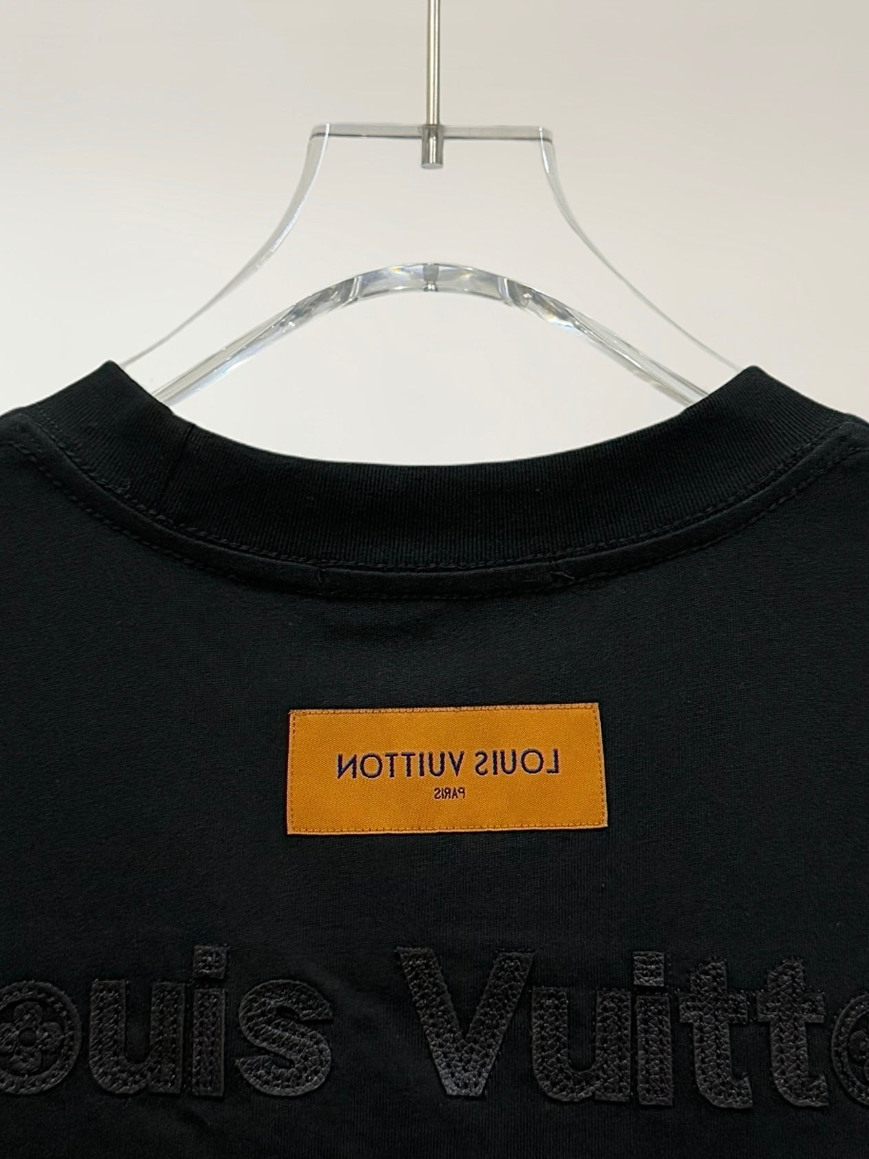 Black T-shirt collar with orange label and embossed Louis Vuitton text