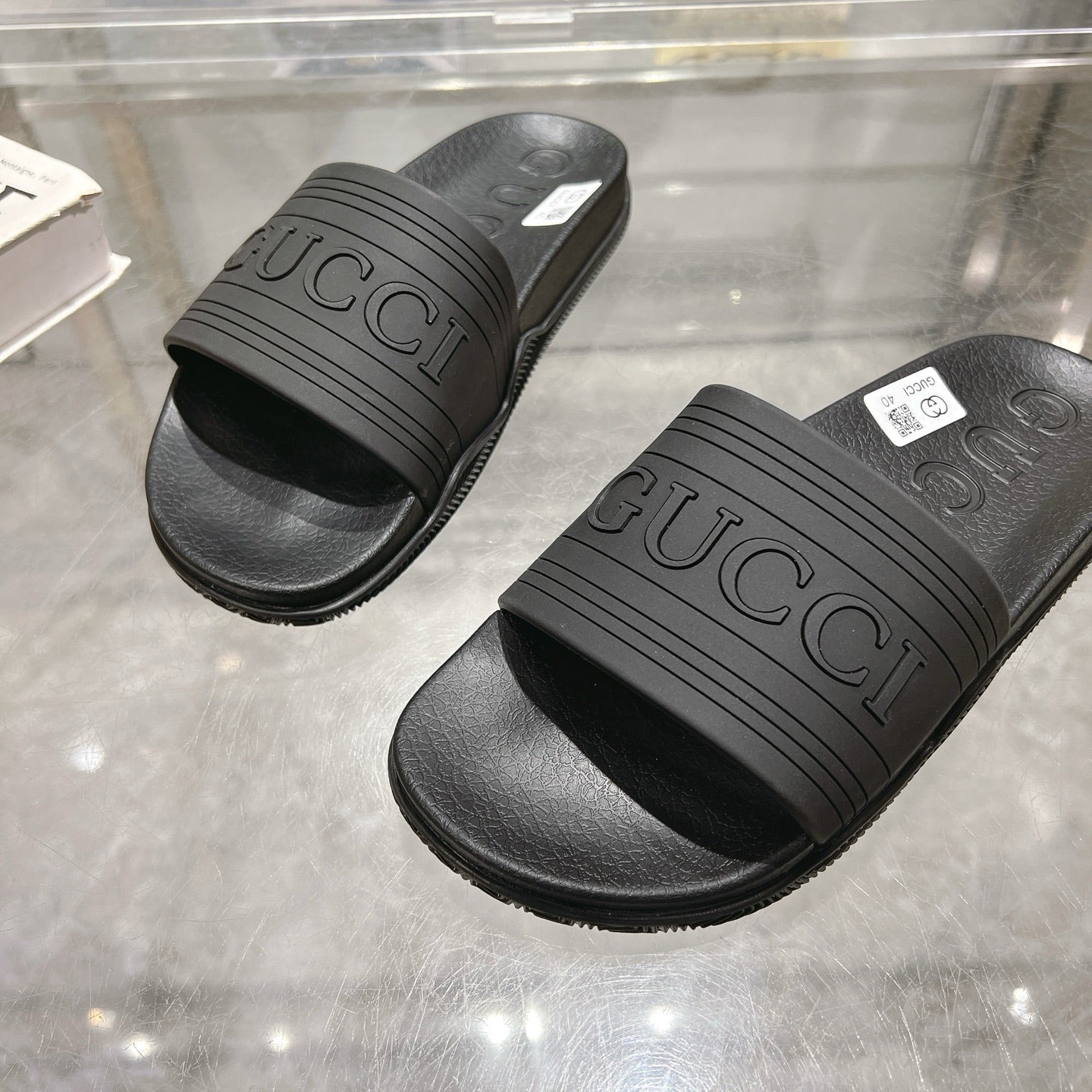 Black Gucci slide sandals, close-up of GUCCI logo strap and textured sole
