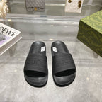 Black Gucci slide sandals with wide logo strap and textured footbed