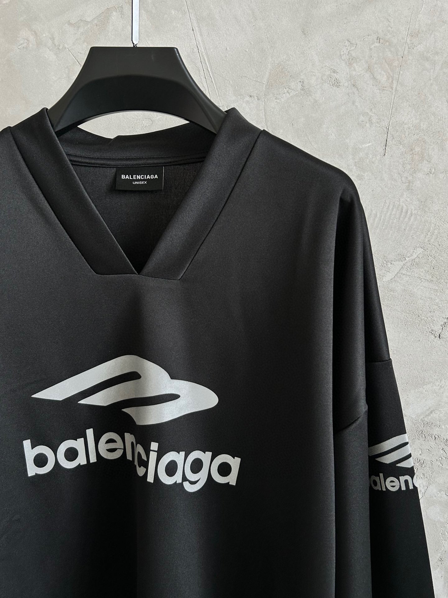 Balenciaga long-sleeve V-neck shirt on hanger with front and partial sleeve logo