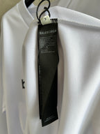 Balenciaga care label hanging from neck of white long-sleeve top