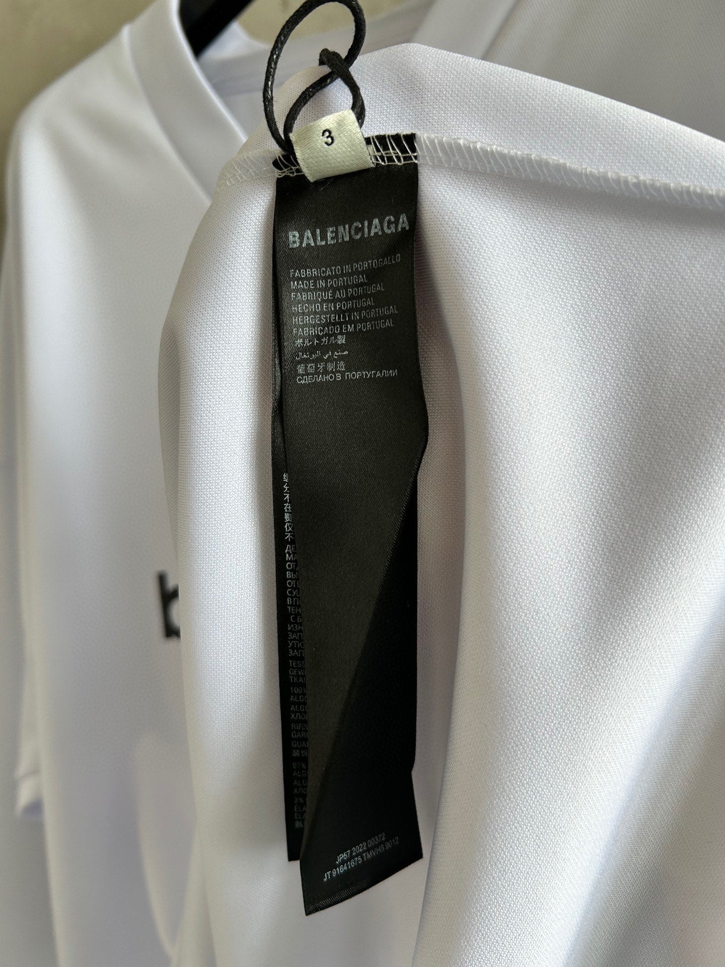 Balenciaga care label hanging from neck of white long-sleeve top