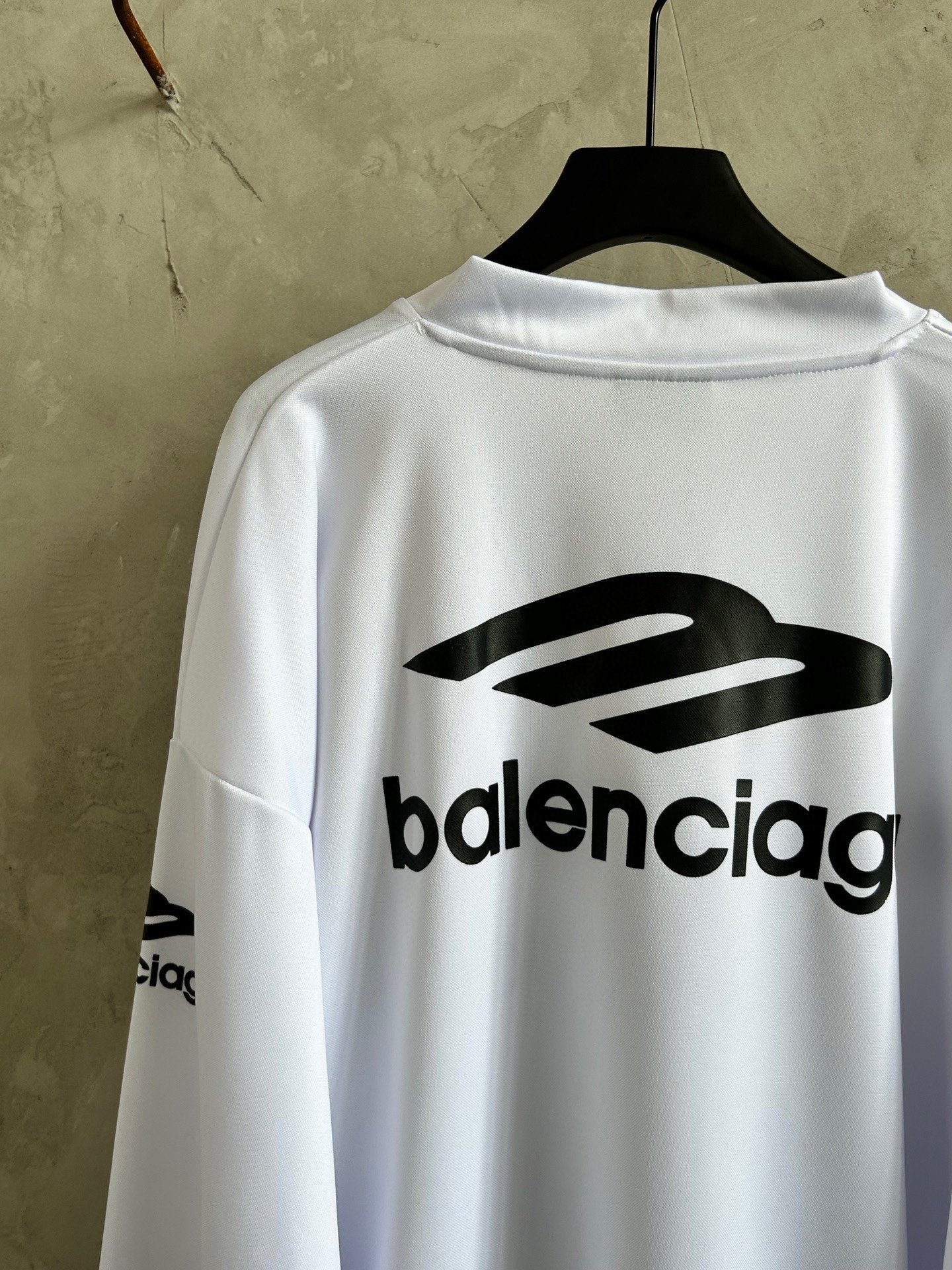Balenciaga logo on back of white long-sleeve top with black emblem