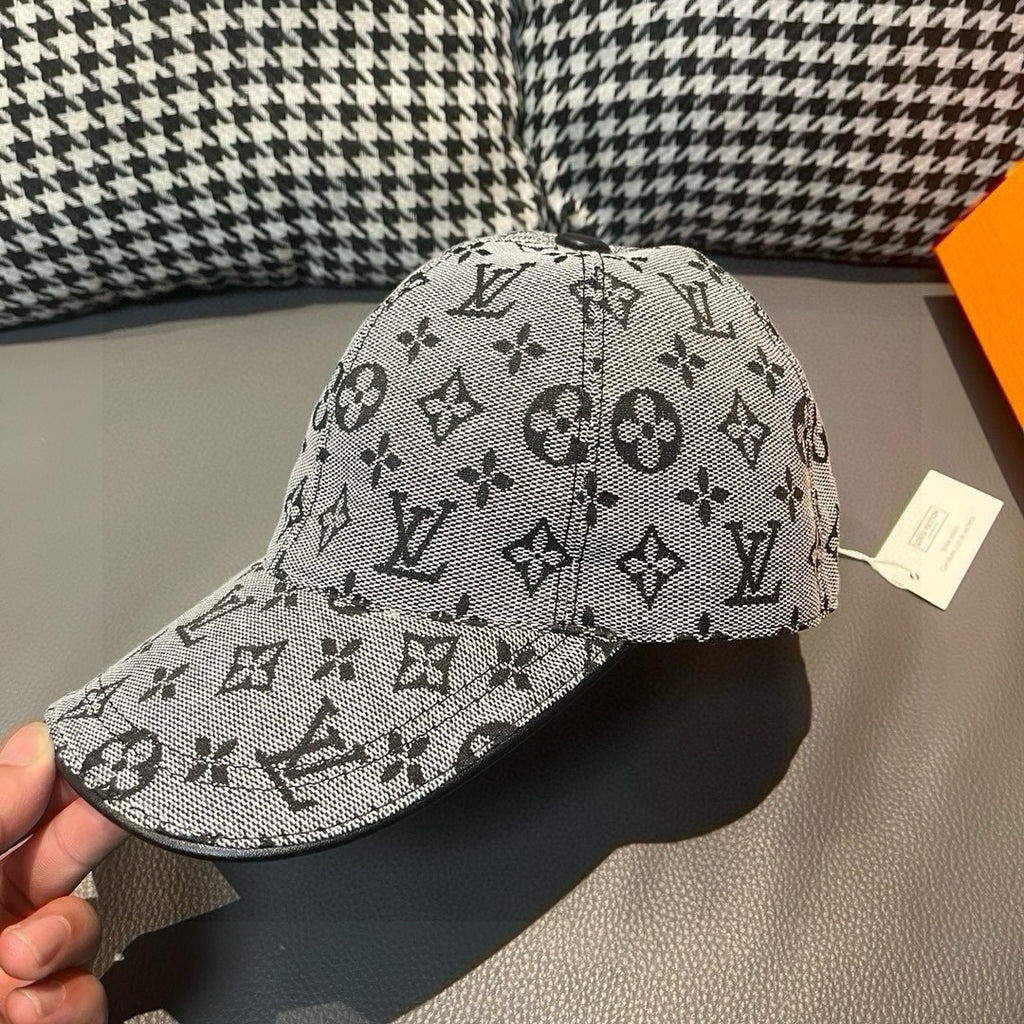 Louis Vuitton cap in light gray with black monogram pattern, held at brim