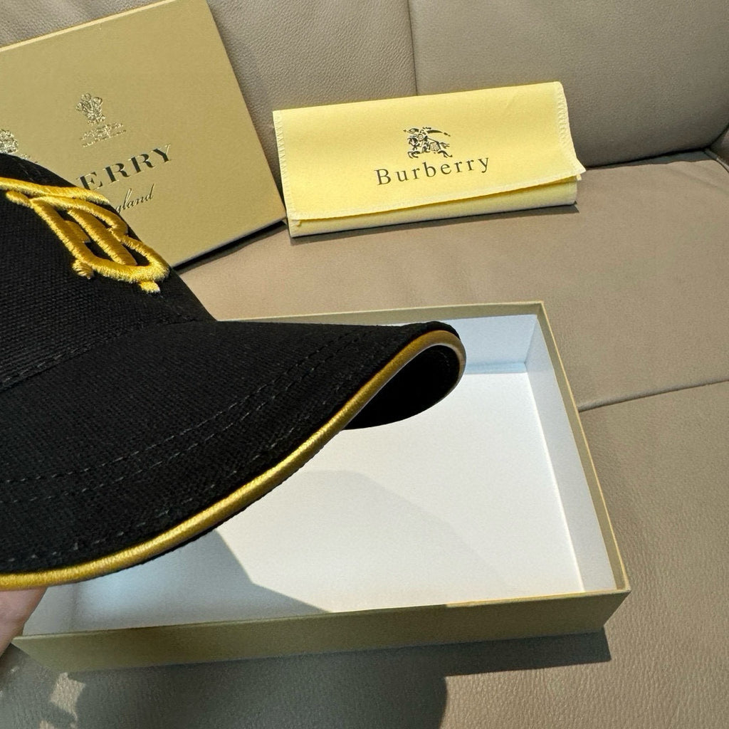 Burberry cap brim in black with gold piping around the edge.