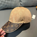 Beige monogram baseball cap with dark logo brim, held at edge