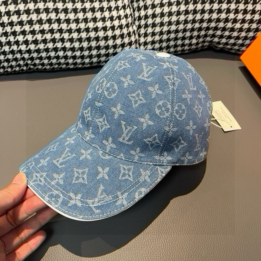 Denim baseball cap held in hand with blue monogram pattern and curved brim