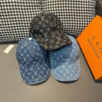 Pair of Louis Vuitton monogram denim caps: blue and black, each with curved brim.