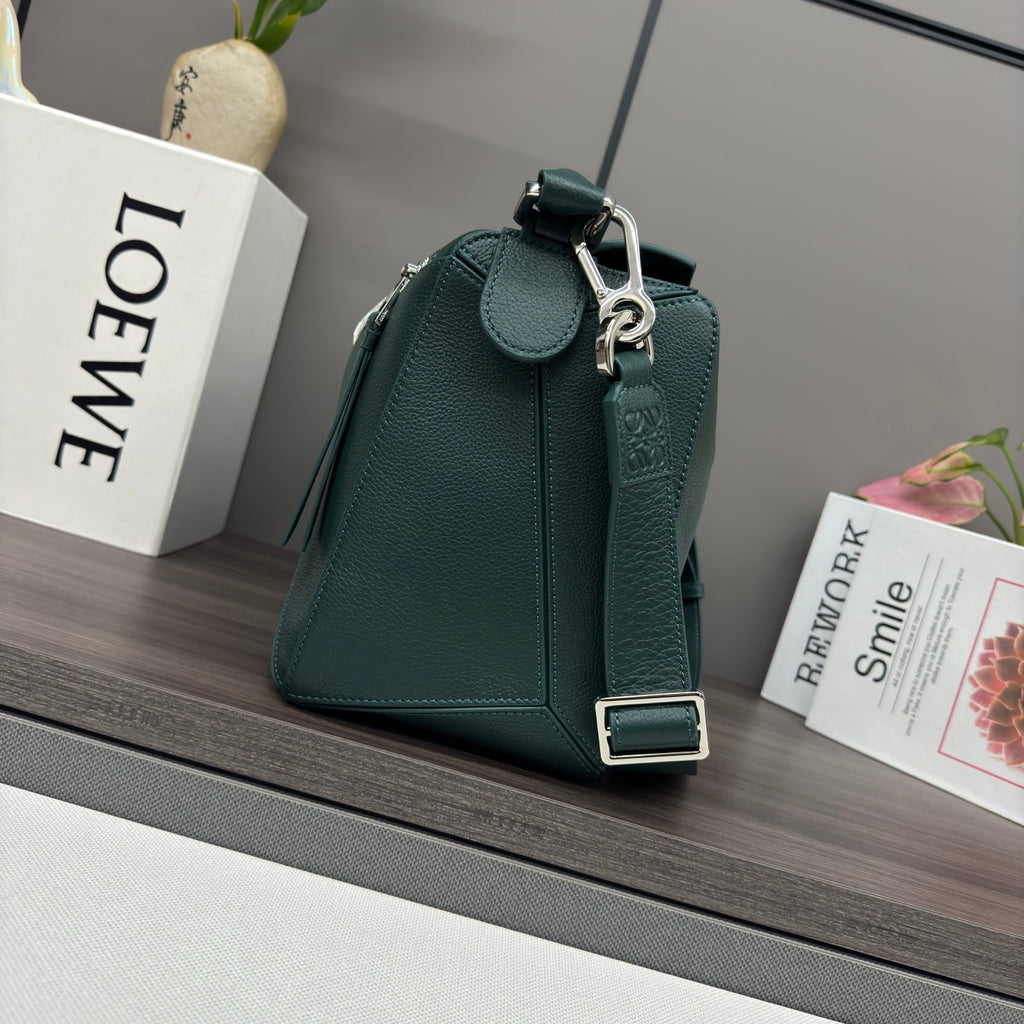 Teal leather crossbody bag with front clasp, metal buckle strap, and rounded top handle.