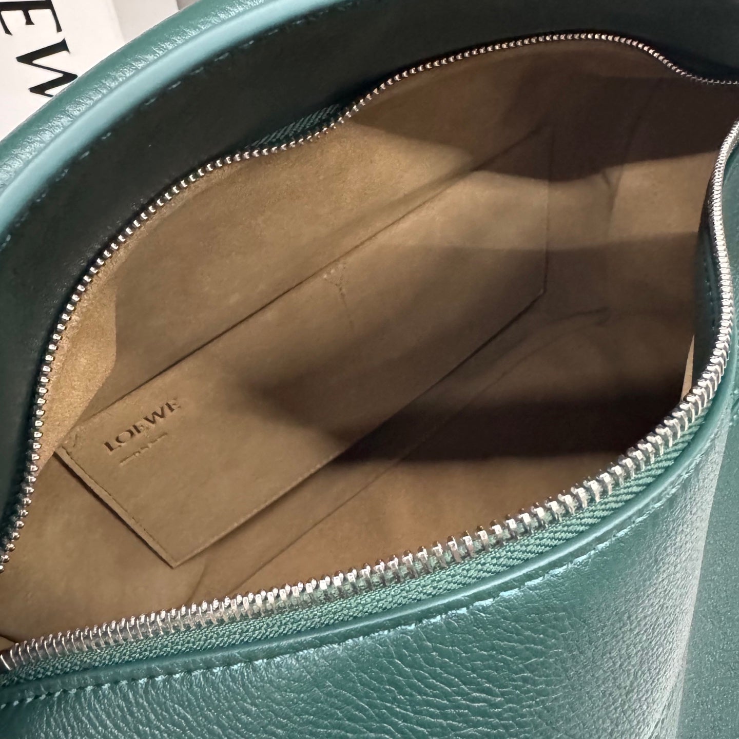 Teal leather bag interior with fabric lining and zippered top opening.