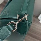 Teal leather bag strap with engraved nameplate connector and polished metal hardware.
