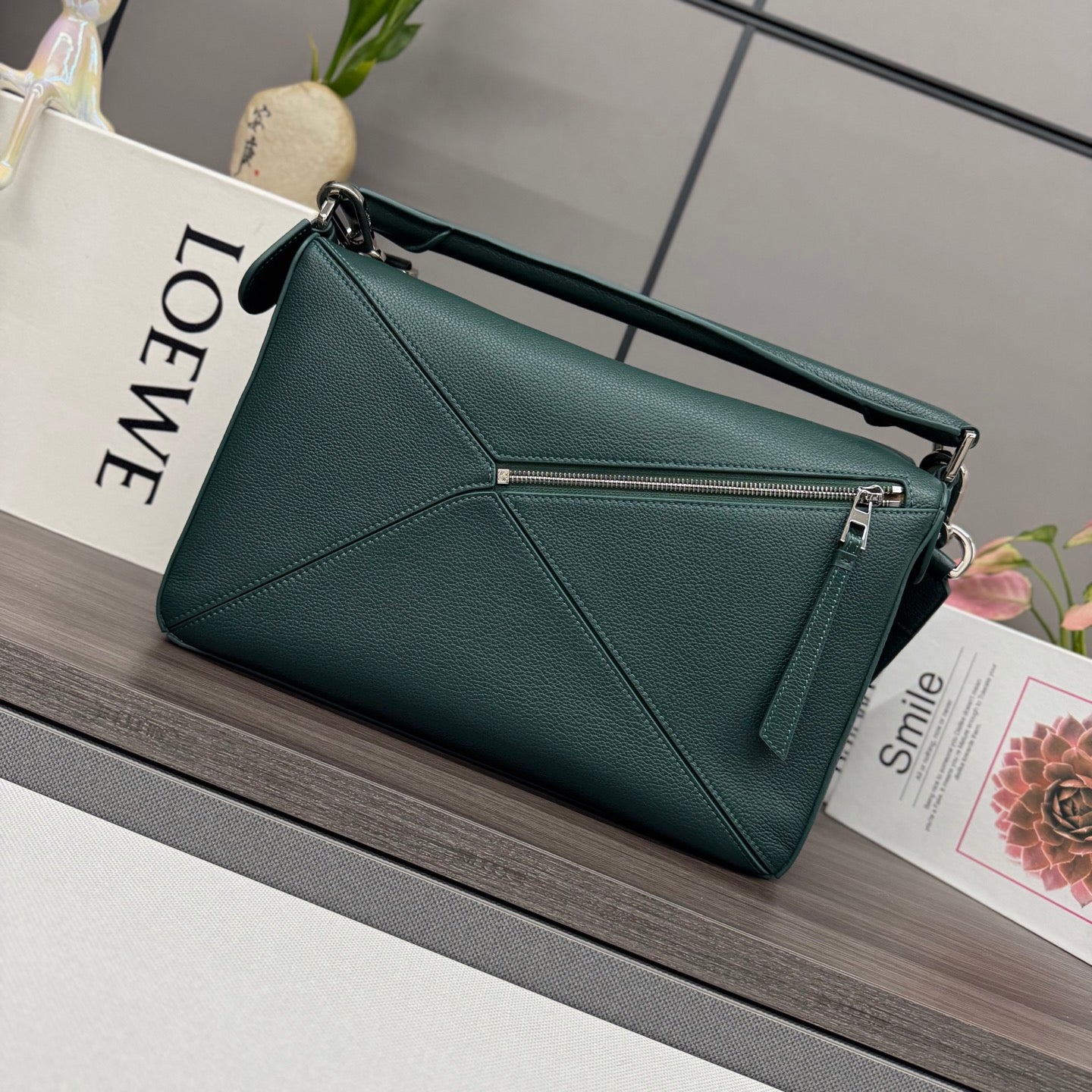 Teal leather satchel bag with zippered front pocket, top handle, and adjustable strap.