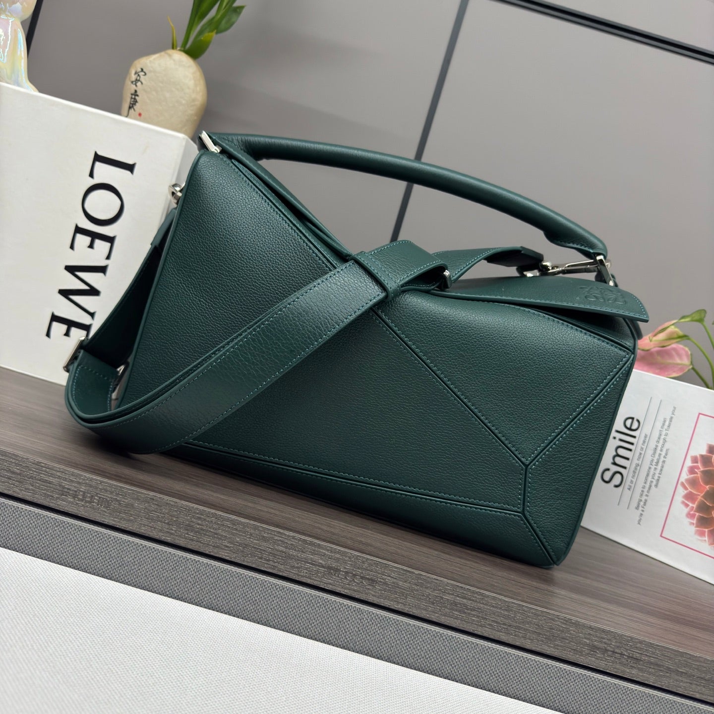 Teal leather shoulder bag with top handle, structured panels, and metal clasp.
